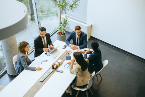 Business people engaged in a meeting discussing strategy and planning in a bright, modern office emphasizing teamwork, communication, and cooperation among colleagues